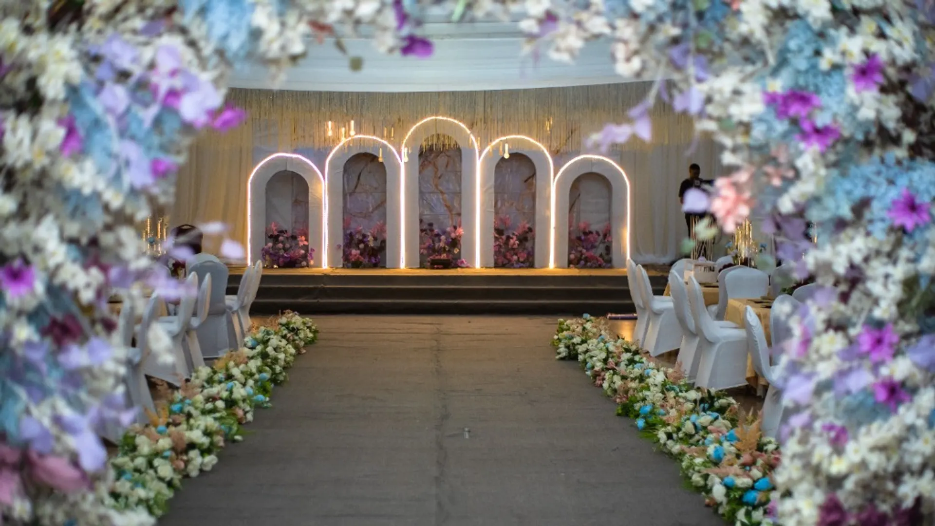 Floral archway leading to a lit arched stage
