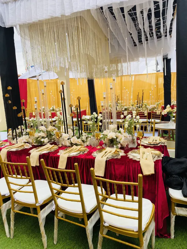 Luxury VIP birthday banquet table draped in crimson velvet with gold Chiavari chairs and crystal chandelier canopy