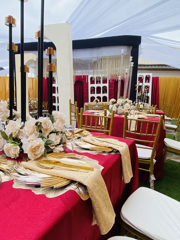 View along styled birthday banquet tables under white drapery canopy towards the stage