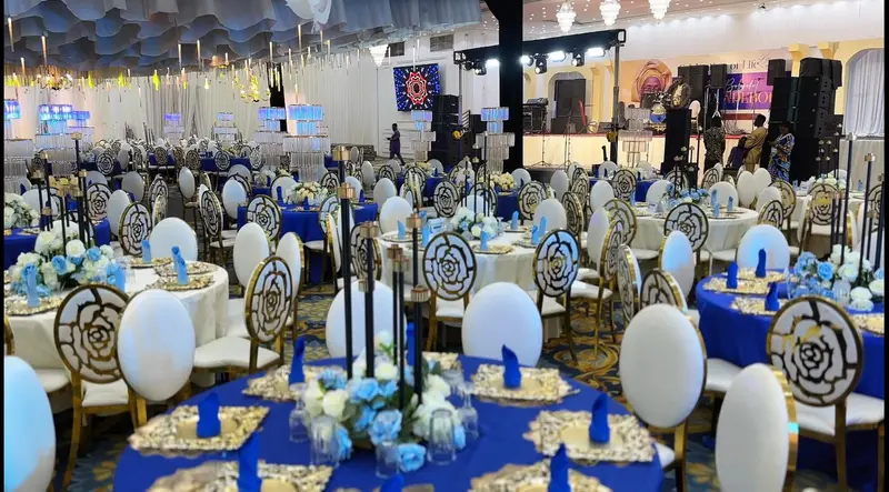 Grand ballroom reception styled with royal blue tables and stage for a celebration of life
